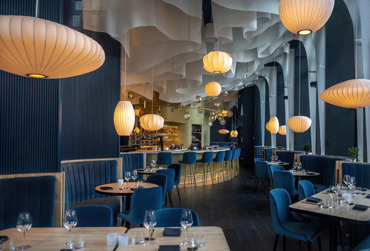 Interiorul cald al unui restaurant, cu mese aranjate și lumină de seară